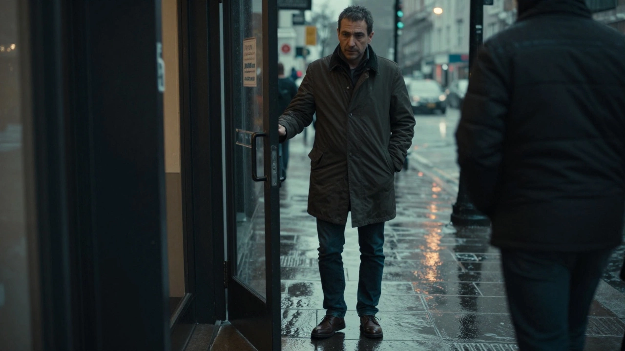 A man holding a door open for a stranger in the rain, polished shoes, calm expression.